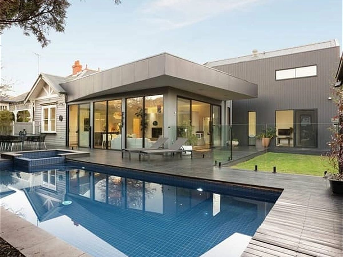 Tiled pool and timber deck beside a grey weatherboard extension
